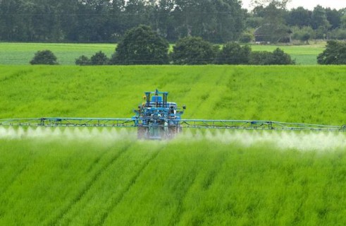 Un engin agricole répand des pesticides dans un champ